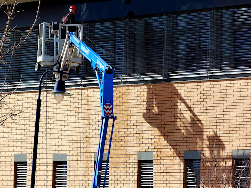 worker in bucket lift soft washing side of commercial building